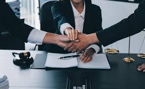 Business professionals joining hands with gavel and scales, symbolizing corporate law and governance with the Law Firm of Dayrel Sewell, PLLC in New York.
