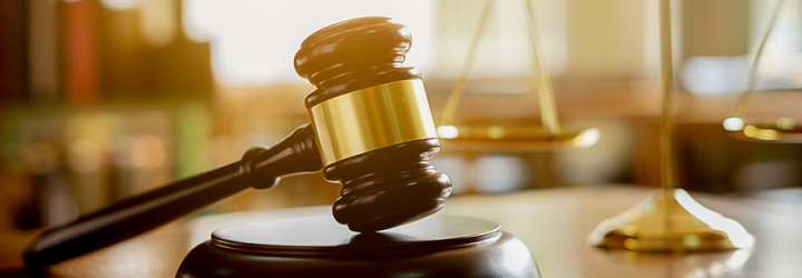 Judge's gavel on a sound block with brass scales of justice in the background